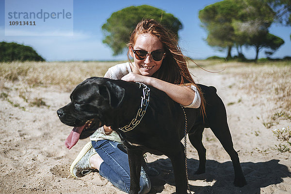 Lächelnde junge Frau mit ihrem Hund in ländlicher Landschaft
