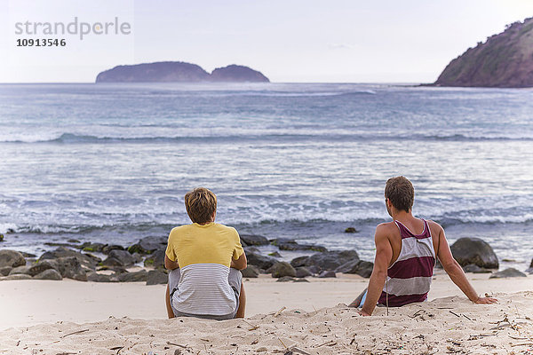 Indonesien  Insel Sumbawa  Zwei junge Männer sitzen am Strand