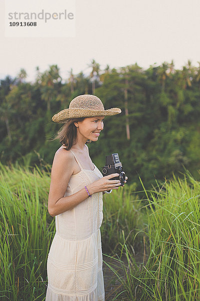 Lächelnde Frau mit Retro-Kamera in der Natur
