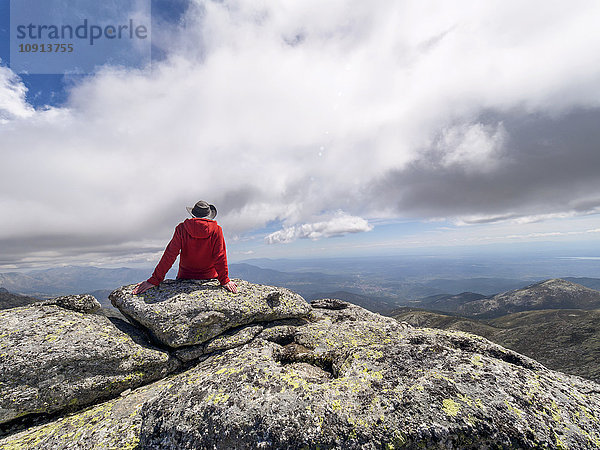 Spanien  Sierra de Gredos  Wanderer auf Felsen in der Berglandschaft sitzend