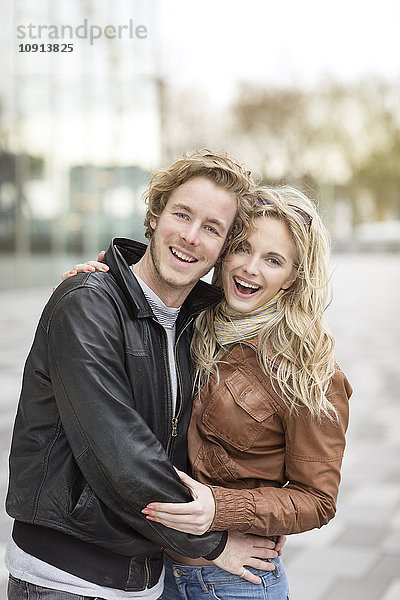 Lachendes junges Paar  das sich in der Stadt umarmt