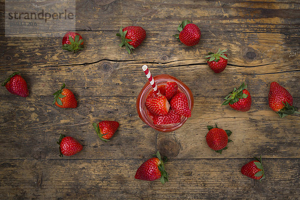 Glas Erdbeer-Smoothie und Erdbeeren auf dunklem Holz