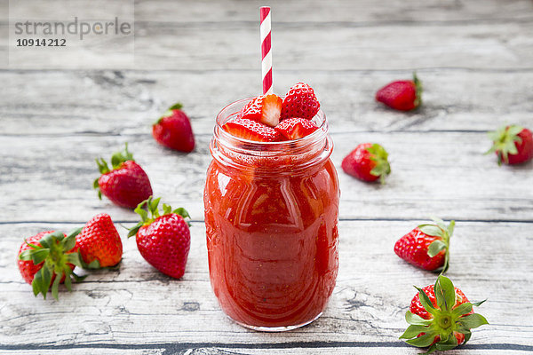 Glas Erdbeer-Smoothie und Erdbeeren auf Holz