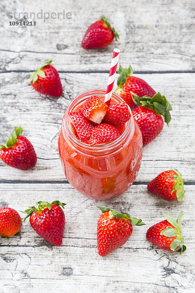 Glas Erdbeer-Smoothie und Erdbeeren auf Holz