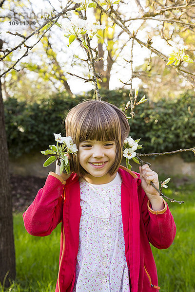 Porträt eines lächelnden kleinen Mädchens mit blühendem Baumzweig