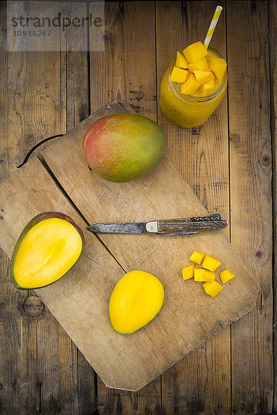 Glas Mango-Smoothie und ganze und geschnittene Mango
