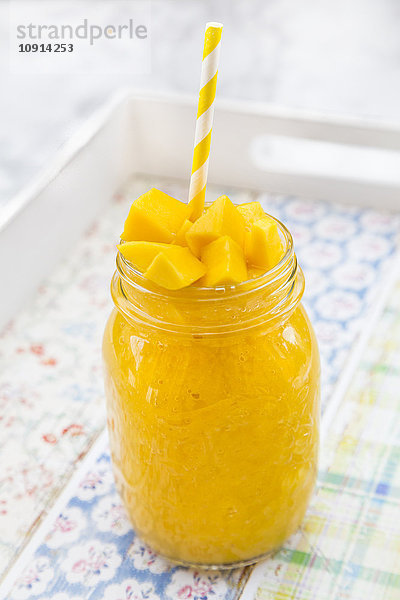 Glas Mango-Smoothie garniert mit gewürfelter Mango