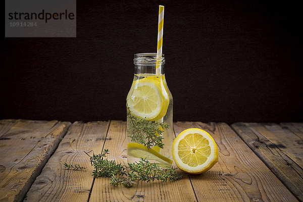 Glasflasche mit Tafelwasser  aromatisiert mit Zitrone und Thymian