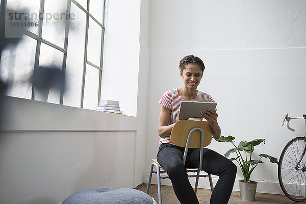 Frau im Stuhl sitzend mit digitalem Tablett