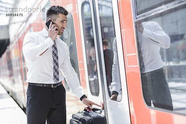 Geschäftsmann am Handy beim Einsteigen in den Zug