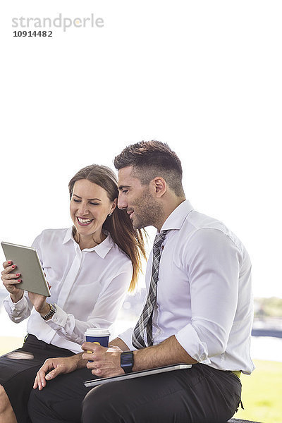 Geschäftsmann und Geschäftsfrau mit digitalem Tablett im Freien