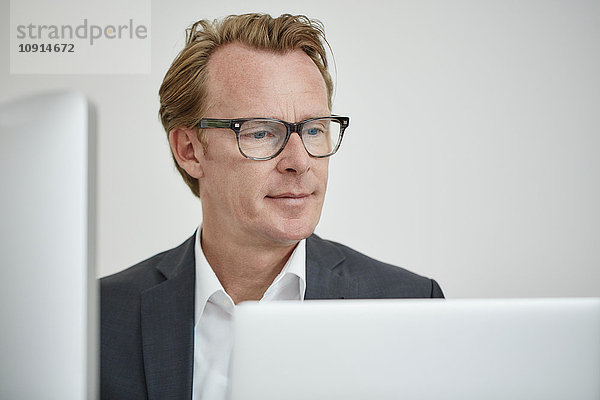 Porträt eines Brillenträgers mit Blick auf den Computer