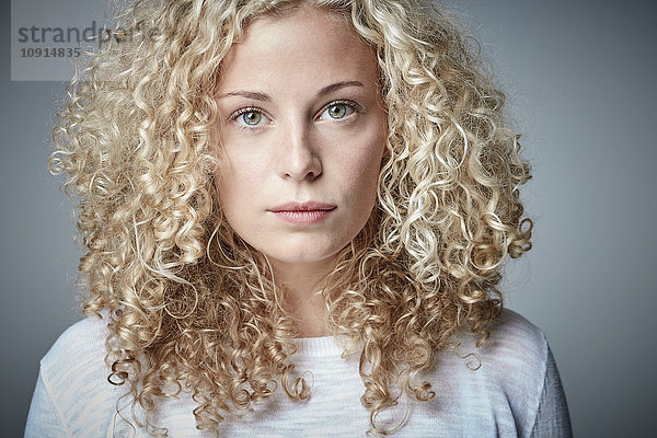 Porträt einer ernsthaften blonden Frau mit lockigem Haar