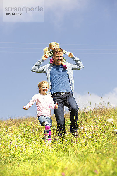 Glücklicher Vater und Tochter beim Spaziergang mit Puppe auf der Wiese