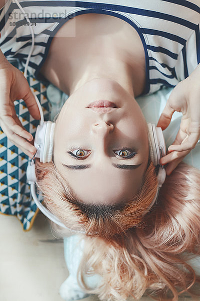 Portrait einer jungen Frau beim Musikhören mit Kopfhörern