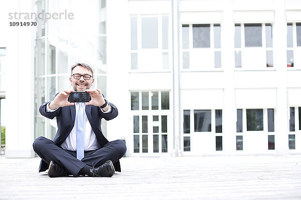 Lächelnder Geschäftsmann im Freien mit einem Selfie