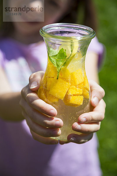 Fruchtaufguss mit Mango  Limette und Zitrone  Mädchen hält Glas