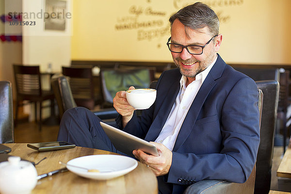 Porträt eines lächelnden Geschäftsmannes  der in einem Café sitzt und Kaffee trinkt.