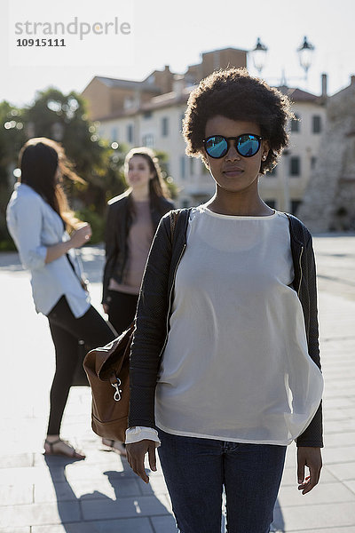 Junge Frau mit Sonnenbrille in der Stadt mit ihren Freunden