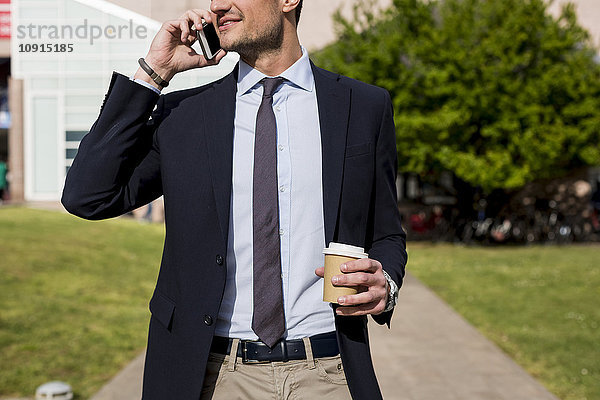 Geschäftsmann im Freien mit Handy und Kaffee zum Mitnehmen