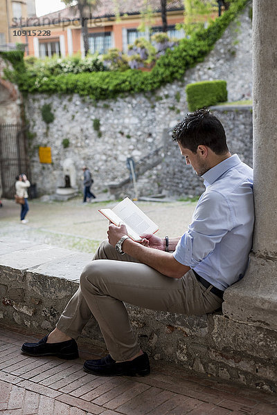 Mann sitzt im Freien und liest Buch