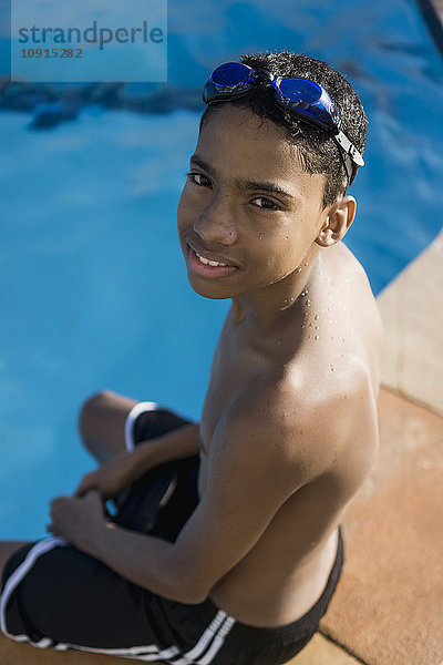 Porträt eines Teenagers  der am Poolrand sitzt.