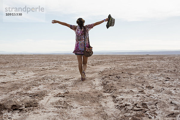 Chile  San Pedro de Atacama  Frau  die mit ausgestreckten Armen in der Wüste unterwegs ist.