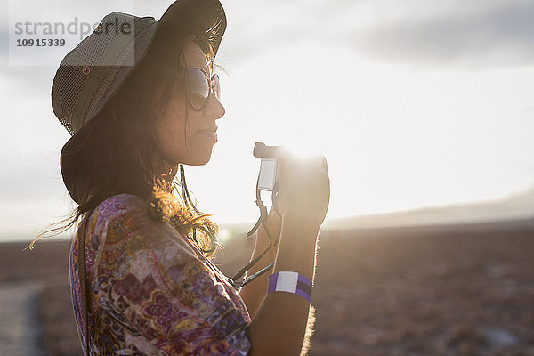 Chile  San Pedro de Atacama  Frau mit Kamera in der Wüste im Gegenlicht