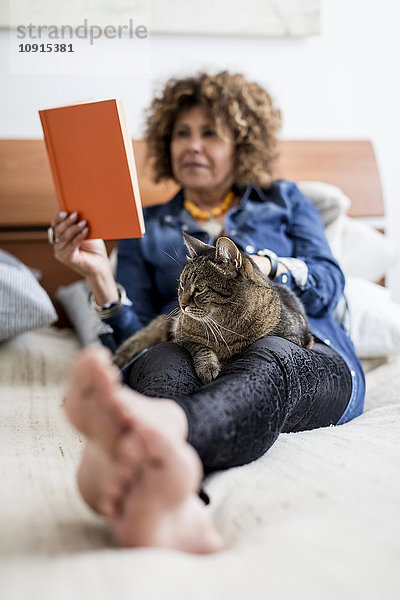 Frau mit Katze auf dem Bett Lesebuch