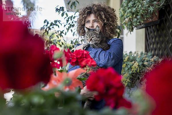 Frau kuschelt mit Katze auf dem Balkon