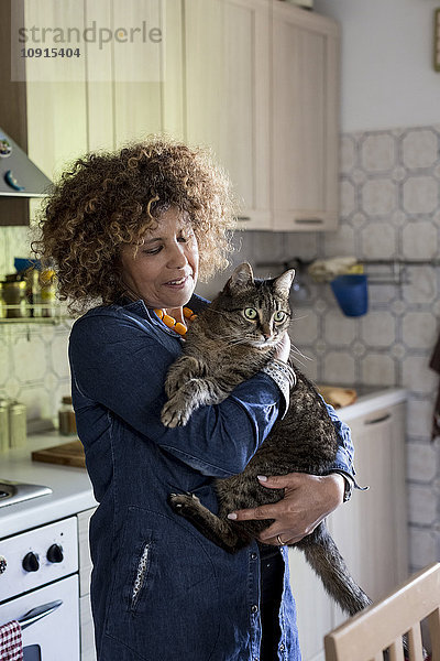 Frau kuschelt mit Katze in der Küche