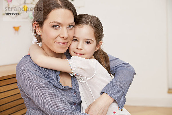 Porträt von Mutter und Tochter  die sich zu Hause umarmen