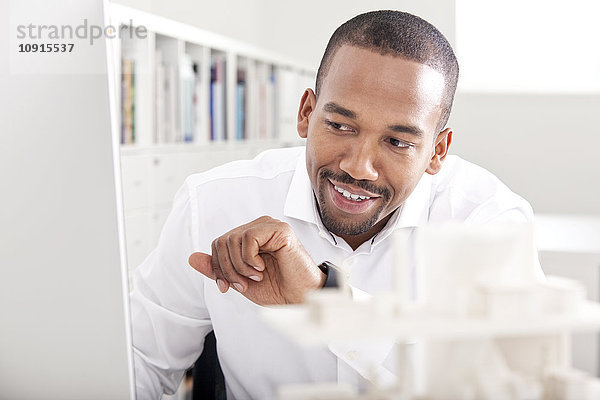 Porträt eines lächelnden Mannes im Büro mit seiner smartwatch