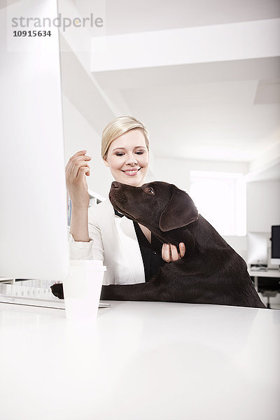 Geschäftsfrau mit ihrem Labrador Retriever im Büro