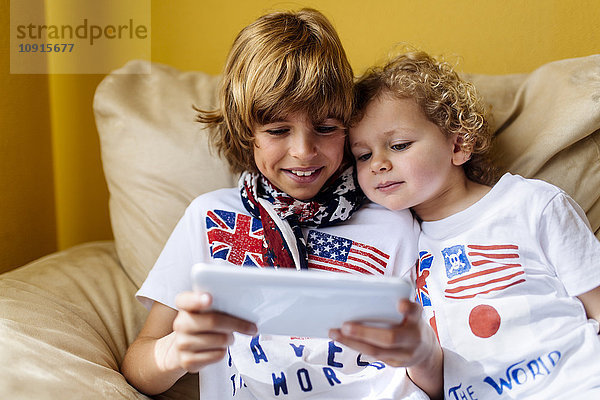 Porträt von zwei Jungen auf der Couch mit digitalem Tablett