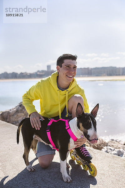 Porträt eines lächelnden Inline-Skaters mit seinem Bullterrier