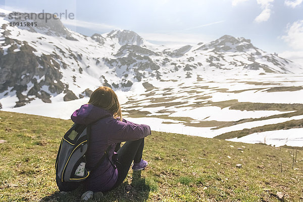 Spanien  Asturien  Somiedo  Frau mit Blick auf die Landschaft auf einer Wiese sitzend