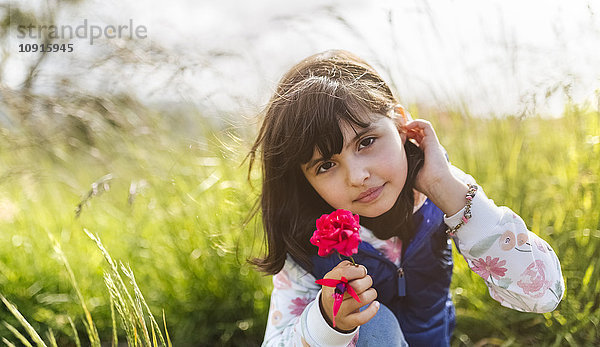Porträt eines kleinen Mädchens mit roter Blume in der Natur