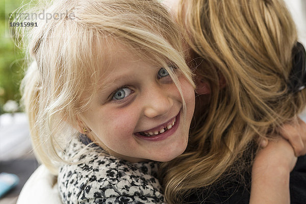 Porträt eines glücklichen blonden Mädchens  das seine Mutter umarmt.