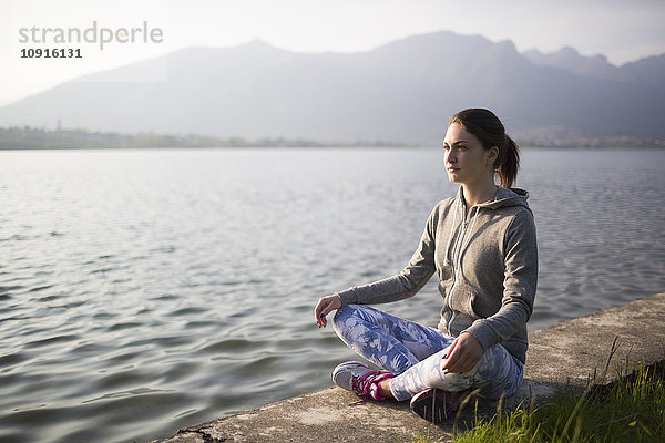 Italien  Lecco  entspannte junge Frau am Seeufer sitzend