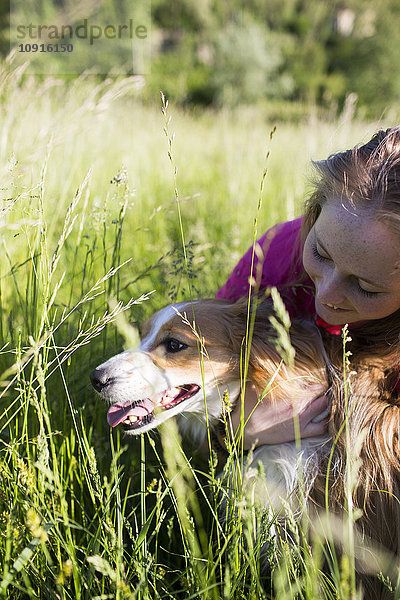 Italien  Lecco  Teenagermädchen mit ihrem Hund auf einer Wiese