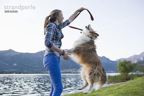 Italien  Lecco  Teenagermädchen spielt mit ihrem Hund am Seeufer