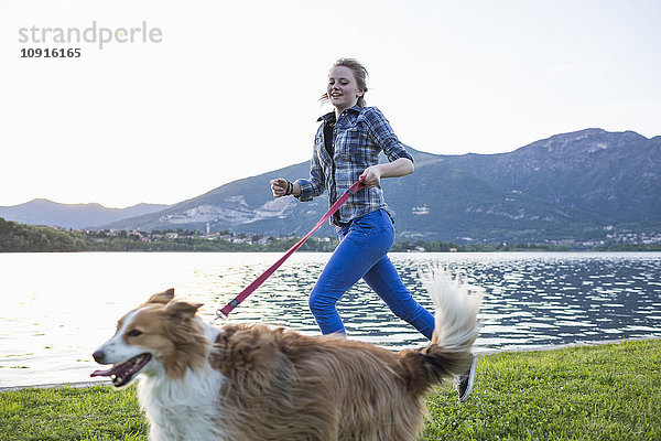 Italien  Lecco  Teenager-Mädchen  das mit ihrem Hund am Seeufer läuft