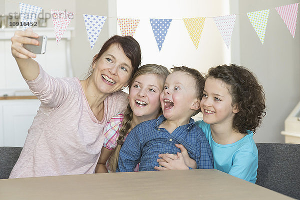 Glückliche Mutter mit drei Kindern  die einen Selfie nehmen.