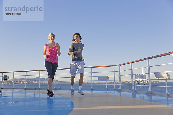 Junges Paar joggt auf dem Schiffsdeck eines Kreuzfahrtschiffes  Mittelmeer