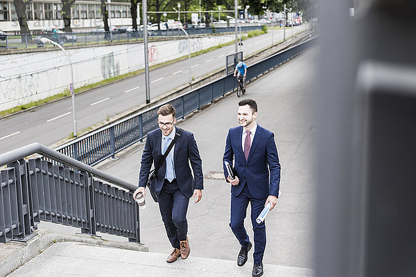 Zwei junge Geschäftsleute  die zusammen in der Stadt spazieren gehen.