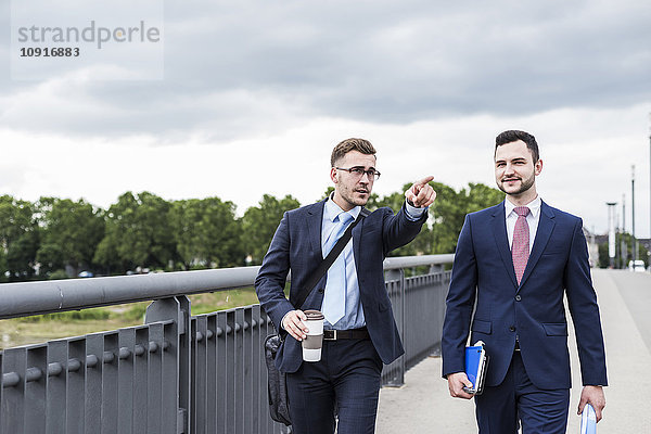 Zwei junge Geschäftsleute  die zusammen in der Stadt spazieren gehen.