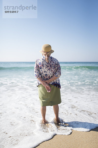 Rückansicht der Seniorin am Strand stehend