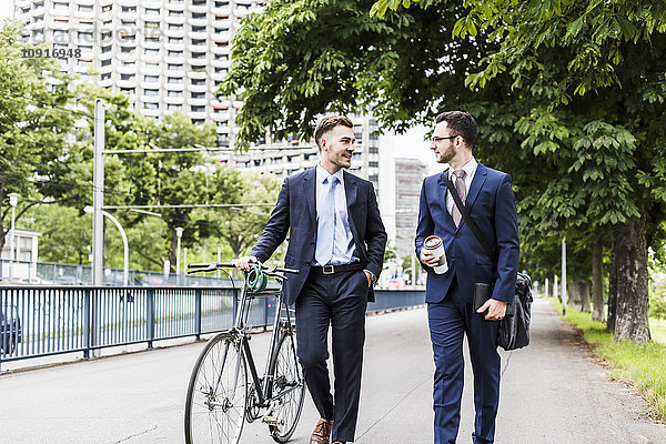 Geschäftsleute  die mit dem Fahrrad in der Stadt spazieren gehen und sich unterhalten.