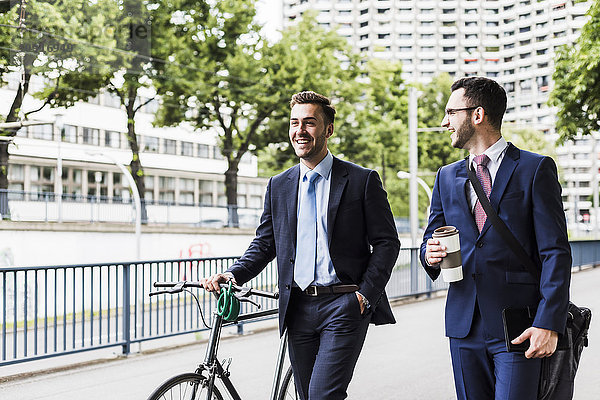 Geschäftsleute  die mit dem Fahrrad in der Stadt spazieren gehen und sich unterhalten.